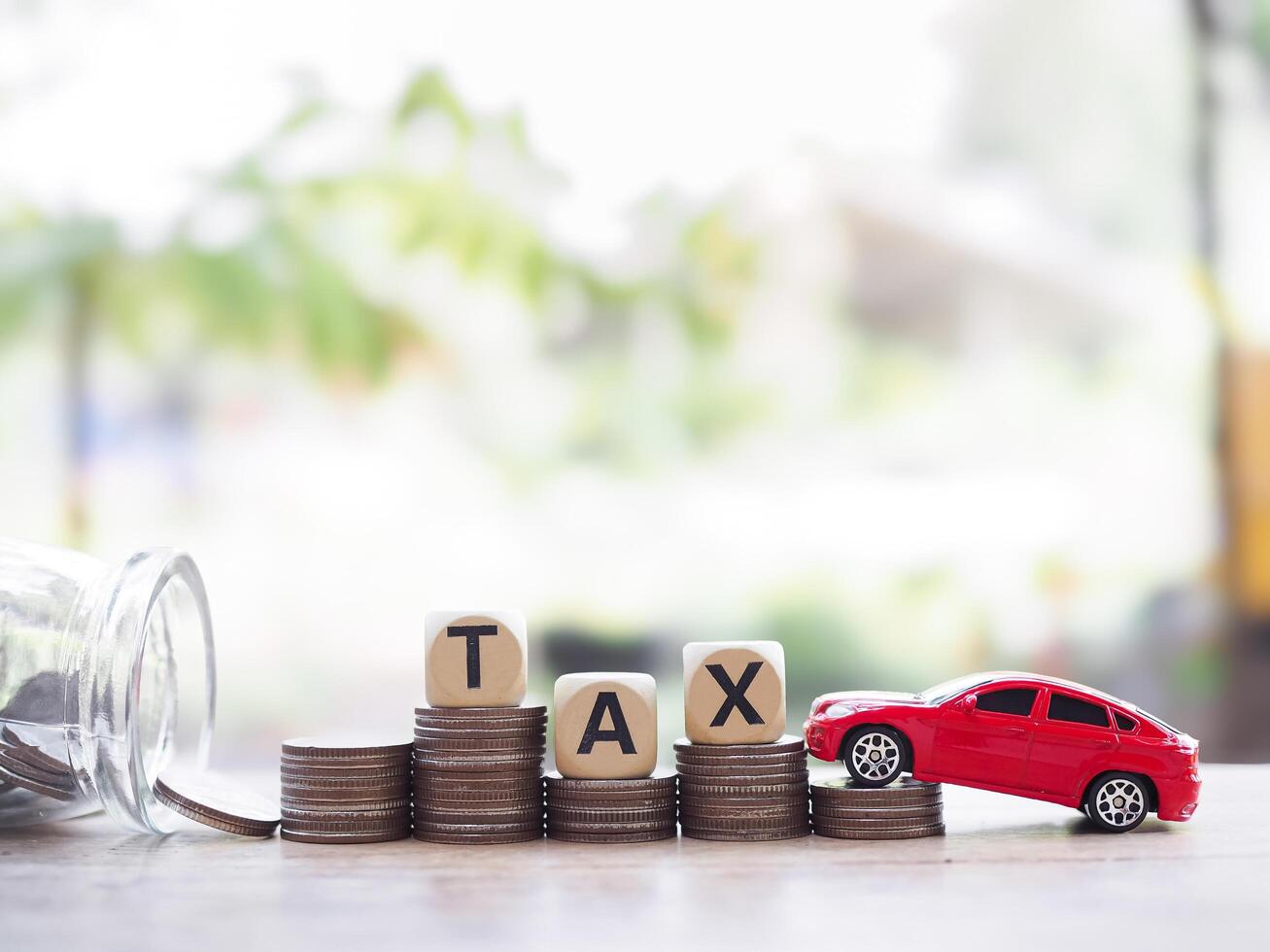 Toy car and wooden blocks with the word TAX on stack of coins. The concept of saving and manage money to success transportation, Paying tax and car loan photo