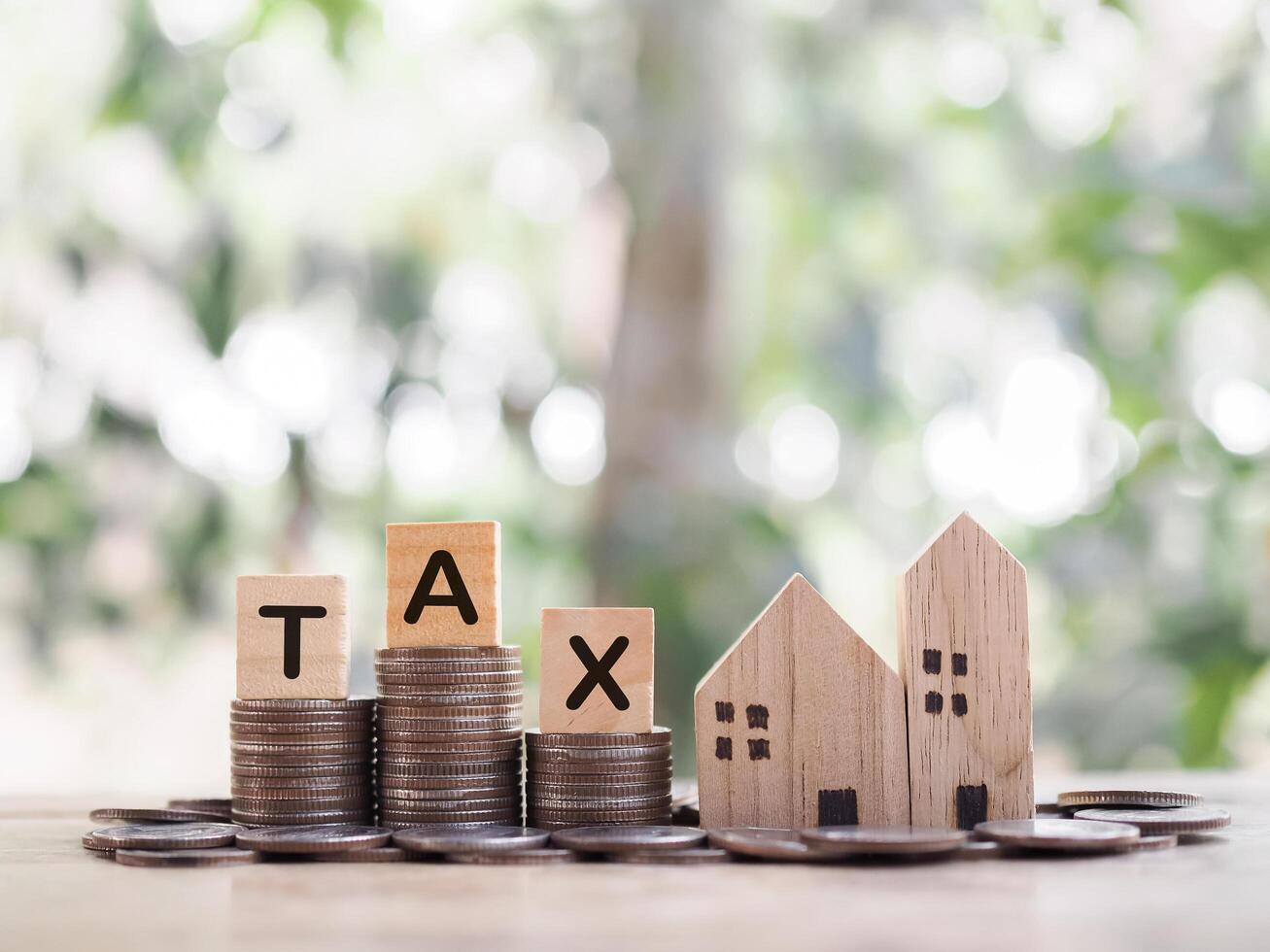 Miniature house and Wooden blocks with the word TAX on stack of coins. The concept of payment tax for house, Property investment, House mortgage, Real estate photo