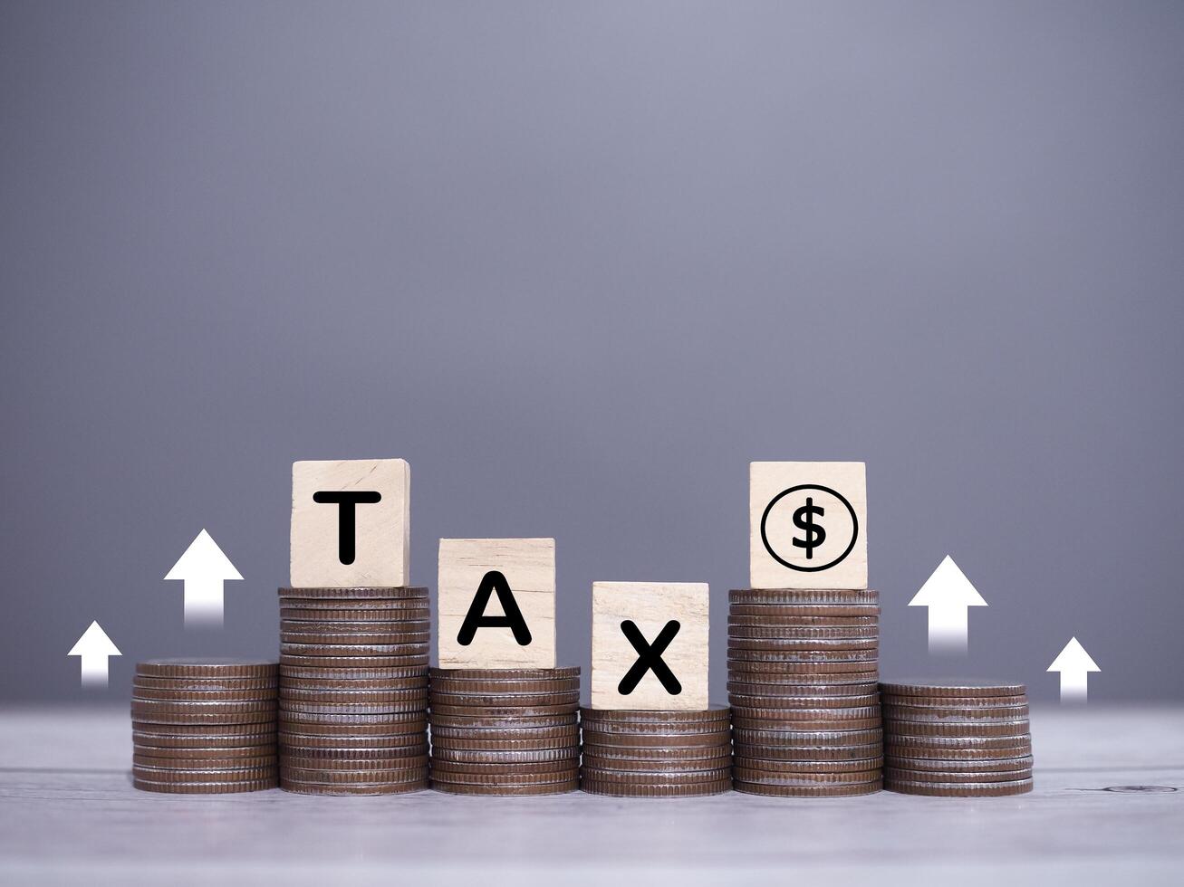 Wooden blocks with the word TAX and dollar coin icons, Stack of coins with arrow rising up icons. The concept about saving money and manage time to paying tax photo