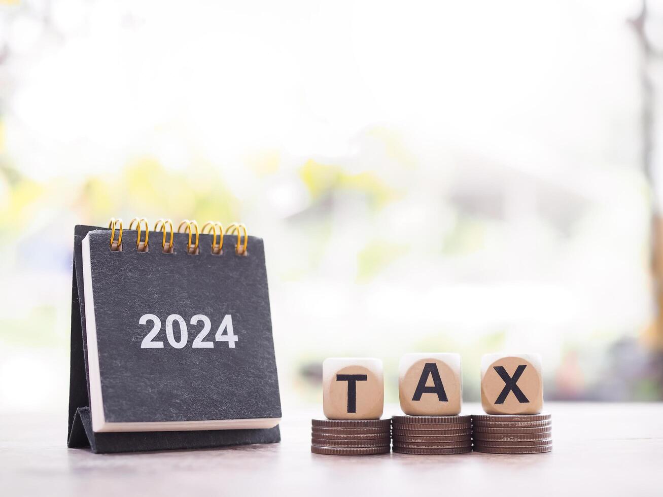 2024 desk calendar, Wooden block with word TAX on stack of coins. The concept of saving money for payment tax, Financial, Investment and Business growing in year 2024. photo