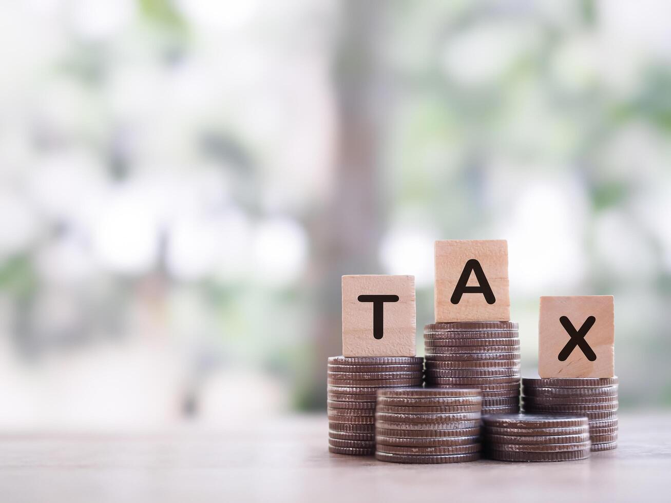 Wooden blocks with the word TAX on stack of coins. The concept about saving money and manage time to paying tax photo