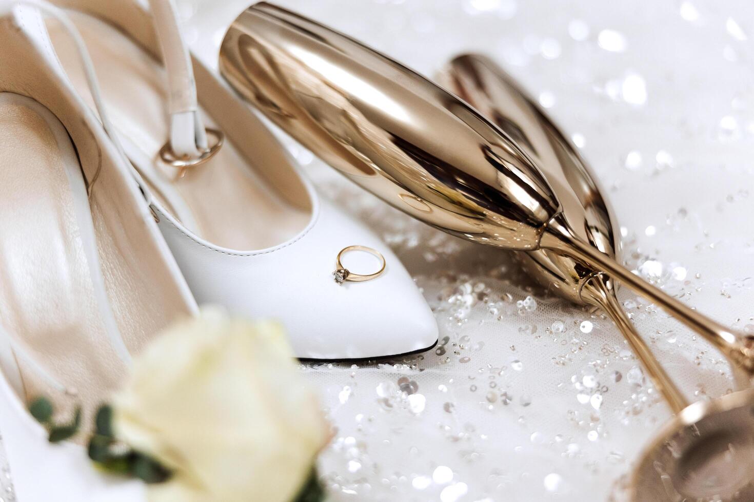 Bride's wedding ring on high-heeled shoes, women's perfume, wedding glasses. Wedding details. High quality photo