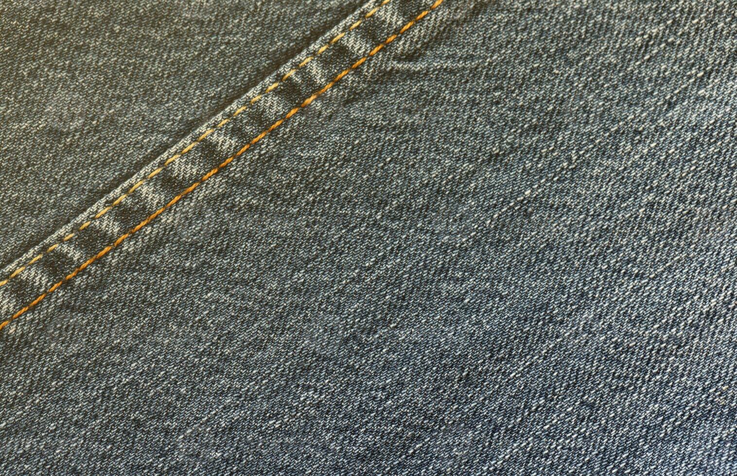 Detailed abstract texture of dark blue denim cloth. Background image of old used denim trousers fabric photo