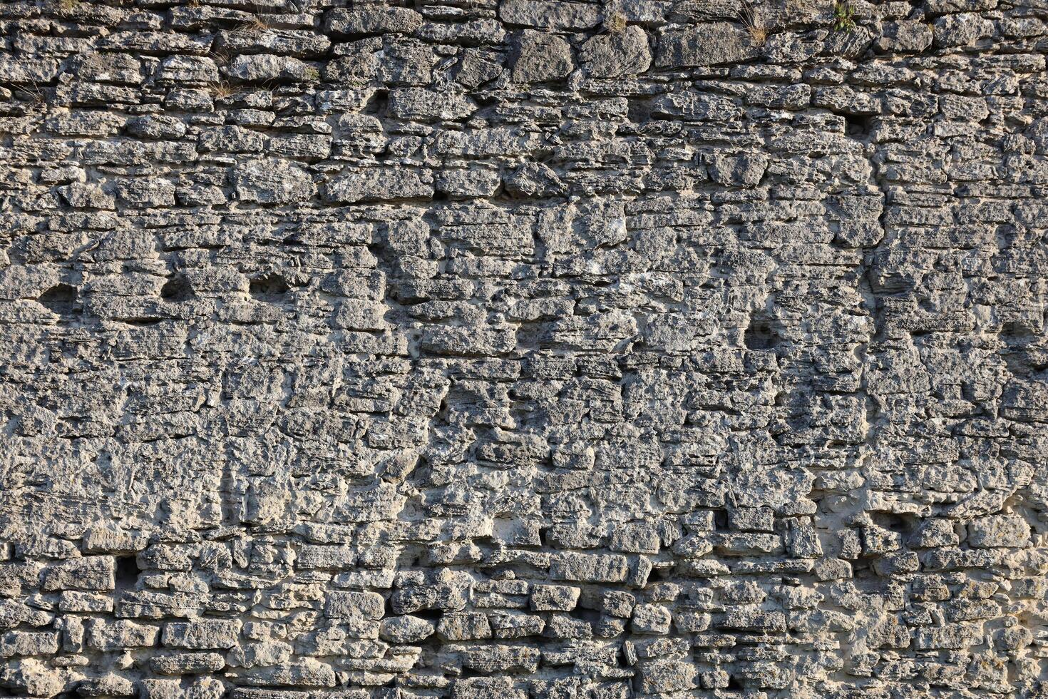 Very old brick stone wall of castle or fortress of 18th century. Full frame wall with obsolete dirty and cracked bricks photo