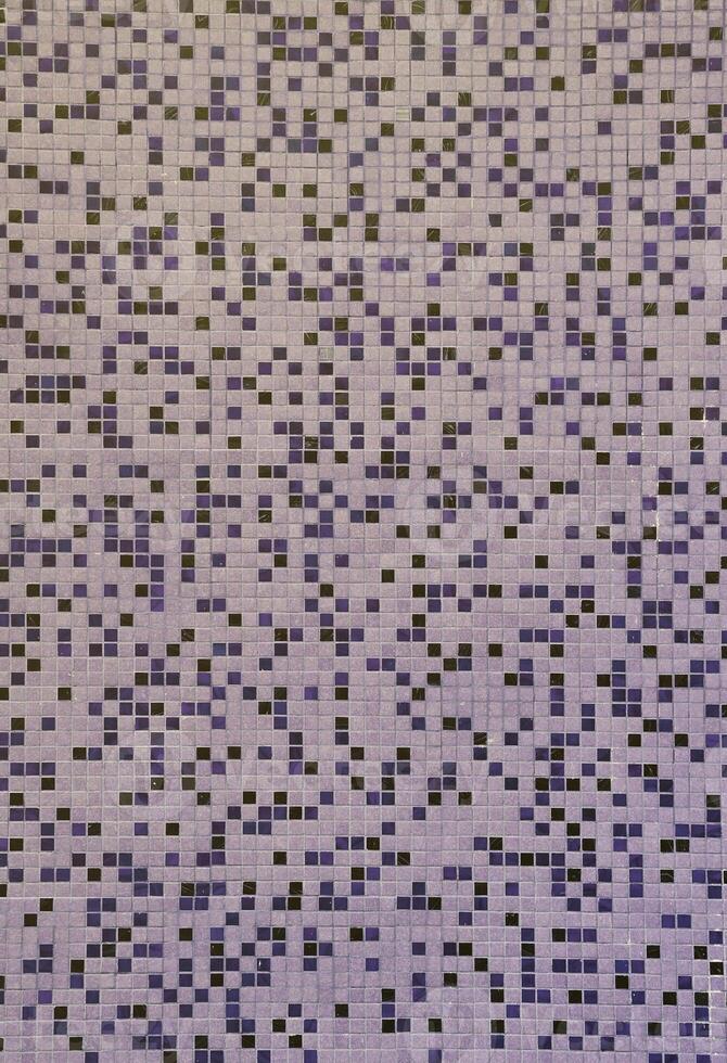 The texture of the wall, decorated with a mosaic of various small square tiles. Abstract pattern of ceramic tiles on the wall photo