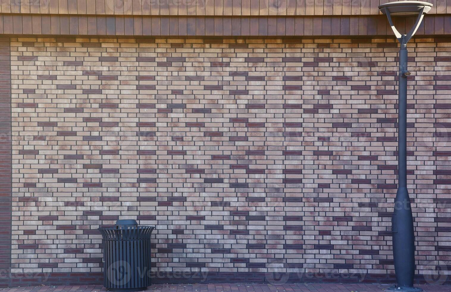 Dark brick wall pattern with masonry. Background texture modern stone wall with lamp post and street trash can photo