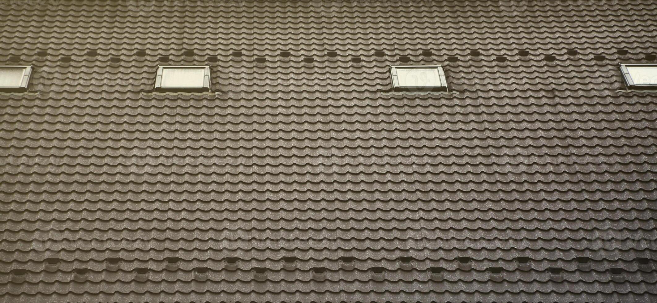 The texture of the roof with a roof made of metal, covered with drops from the rain. Several pane windows are built into the roof photo
