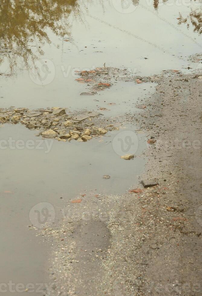 Photo of a fragment of a destroyed road with large puddles in rainy weather