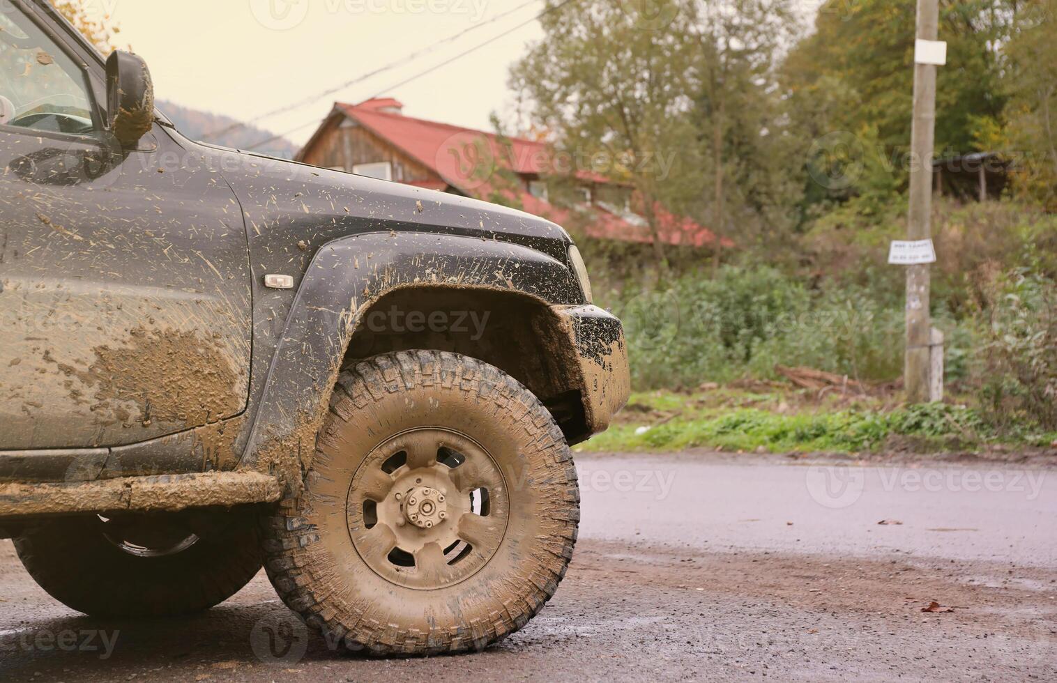 Wheel closeup in a countryside landscape with a mud road. Off-road 4x4 suv automobile with ditry body after drive in muddy road photo