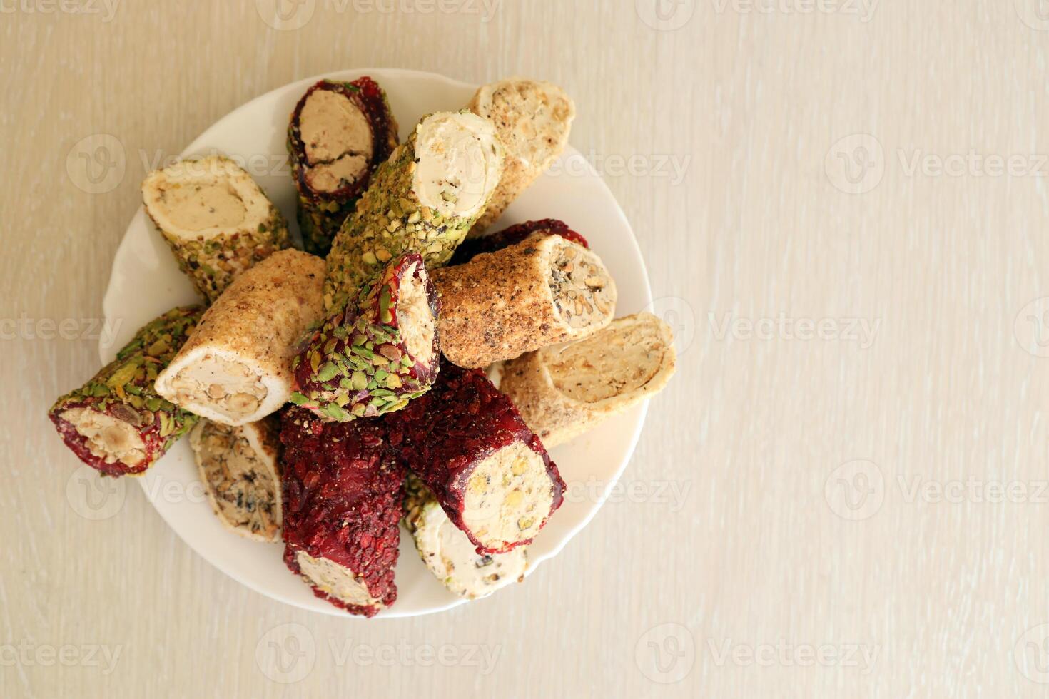 muchos rollos de turco deleite con diferente sabores y empastes en blanco plato en mesa. cortes de turco lokumu foto