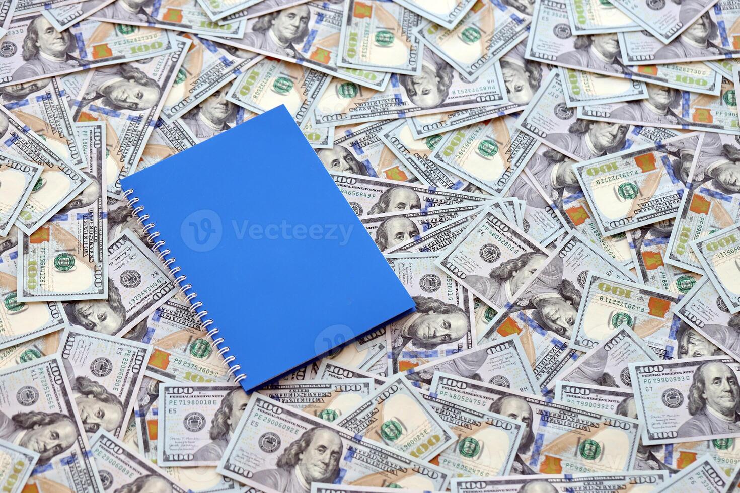 Office workplace table with blank notebook or notepad and many hundred dollar bills photo