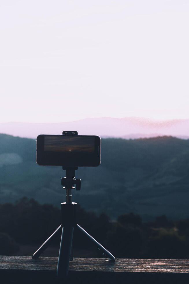 A smartphone is recording the sun setting over a mountain range. photo