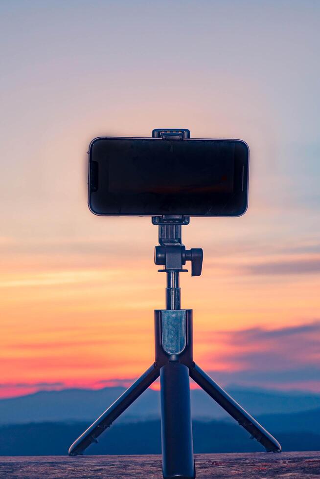 A smartphone is recording the sun setting over a mountain range. photo