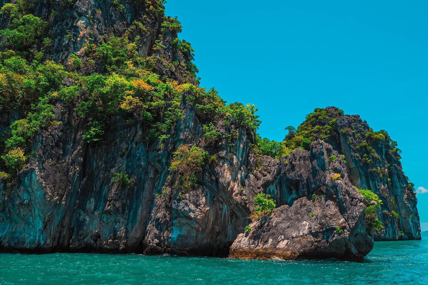 Aerial panorama of Thailand's verdant, lush tropical island, National Park Island, with blue and aquamarine the sea, and clouds shining by sunlight in the background. photo
