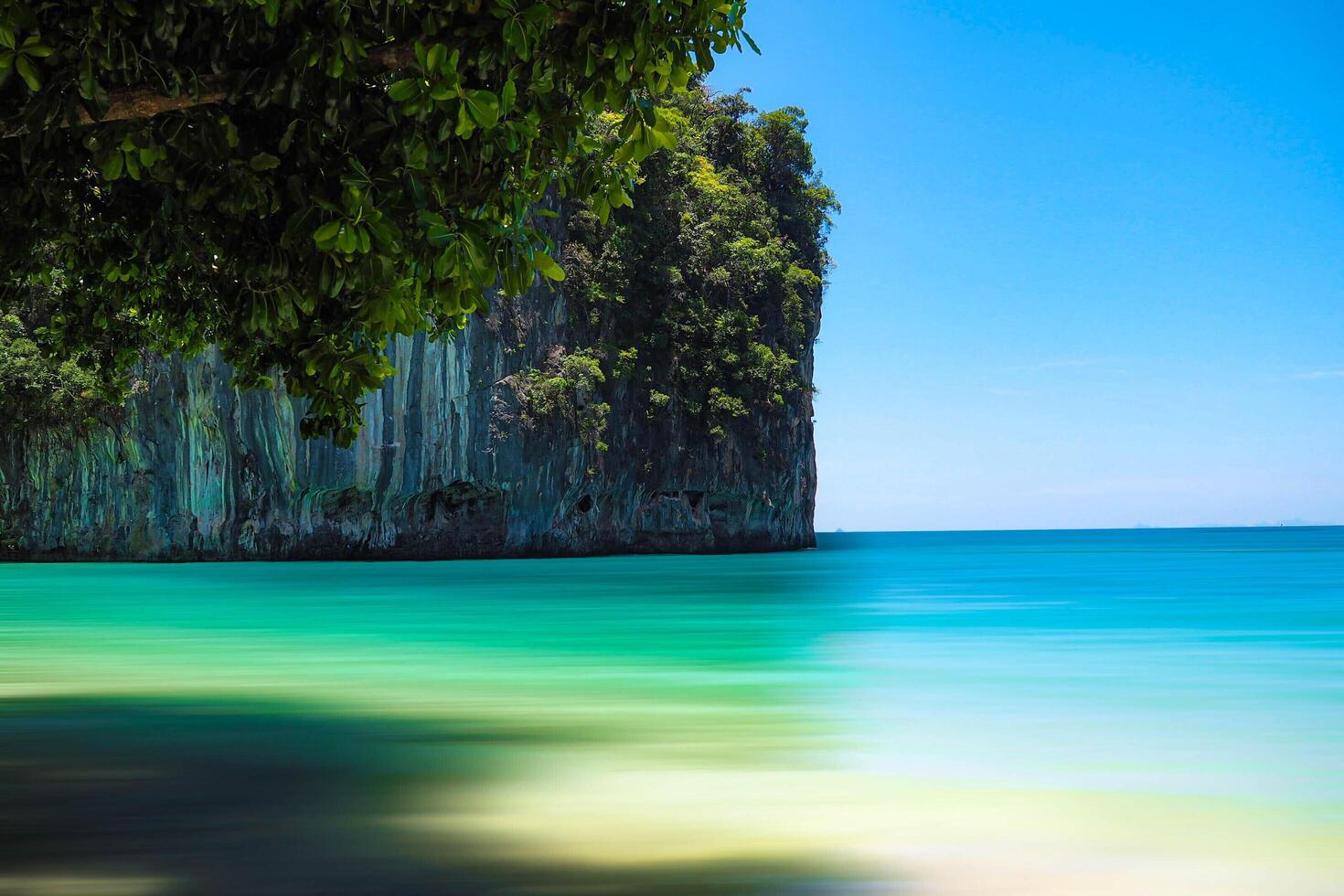 Aerial panorama of Thailand's verdant, lush tropical island, National Park Island, with blue and aquamarine the sea, and clouds shining by sunlight in the background. photo