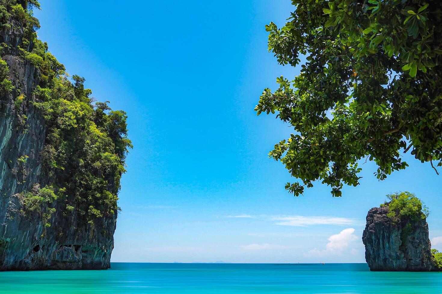 Aerial panorama of Thailand's verdant, lush tropical island, National Park Island, with blue and aquamarine the sea, and clouds shining by sunlight in the background. photo