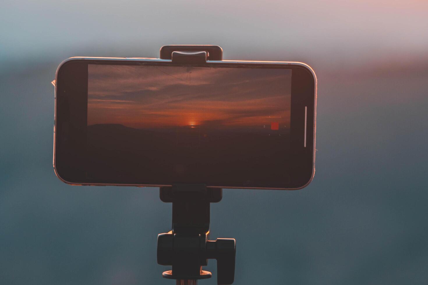 A smartphone is recording the sun setting over a mountain range. photo