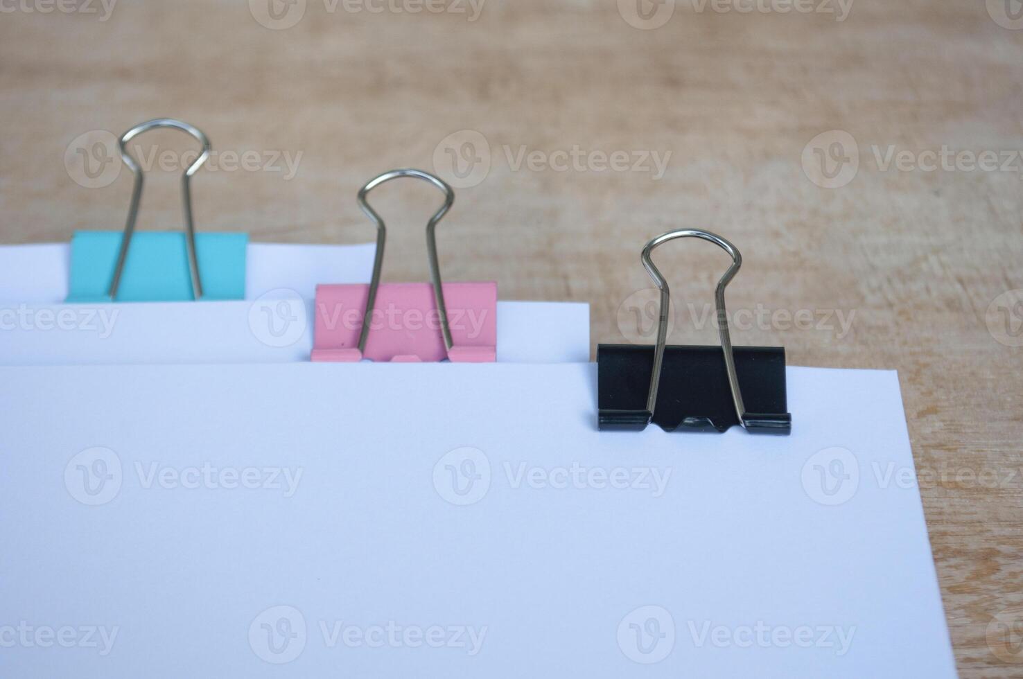 Side view of blank document papers with paper clips pastel on wooden table. Documentation concept photo
