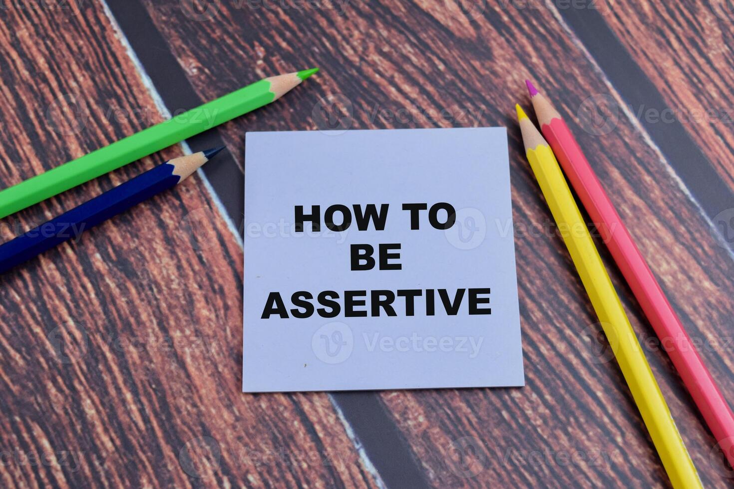 Concept of How to be Assertive write on sticky notes isolated on Wooden Table. photo