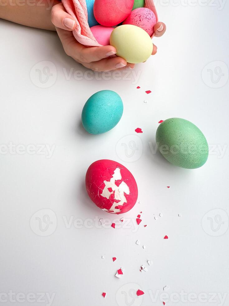 Hands holding colorful painted Easter eggs with one cracked egg on the side, representing Easter festivities, spring celebrations, and family fun activities. photo