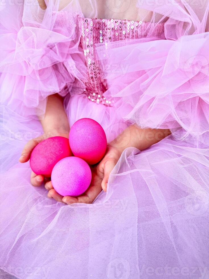 Child in pink tulle dress holding bright pink eggs, Easter celebration concept with a playful and festive feel. For Easter related marketing materials, event invitations, childrens party photo