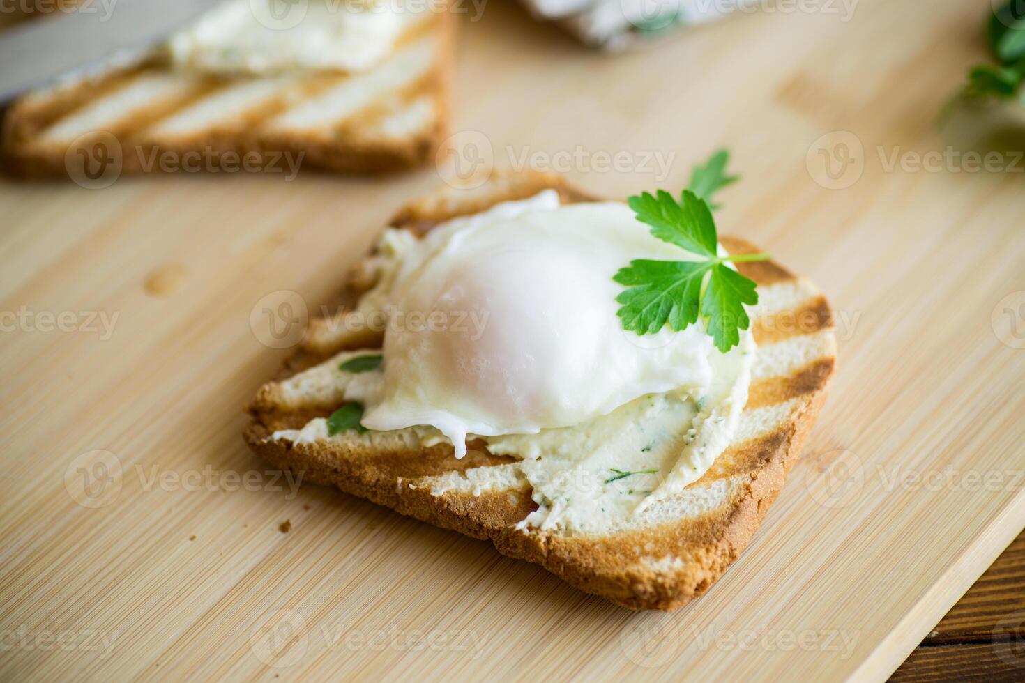 Fried toast bread with spread and poached egg, on a wooden table. photo