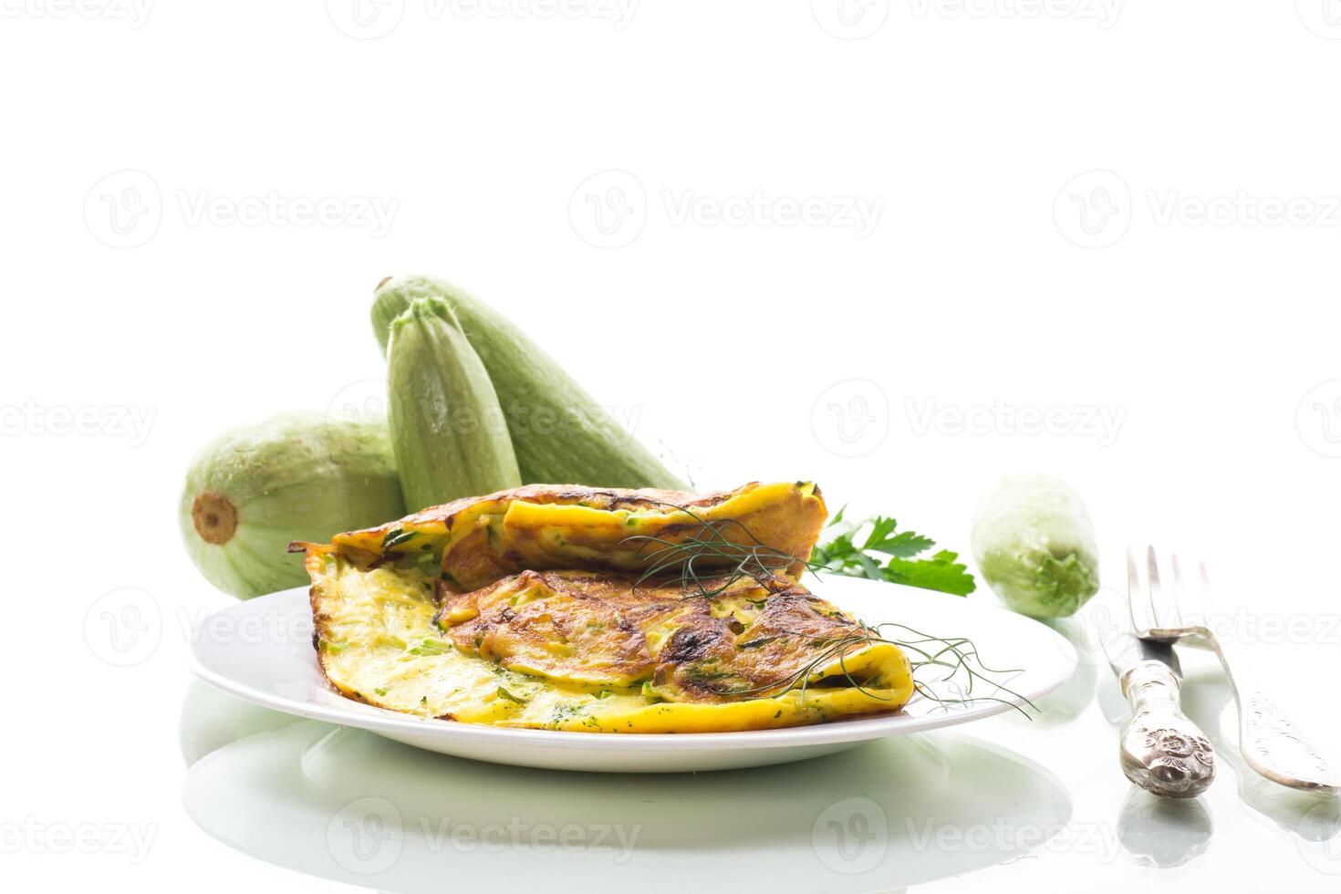 Fried omelette with zucchini,in a plate on a white background. photo