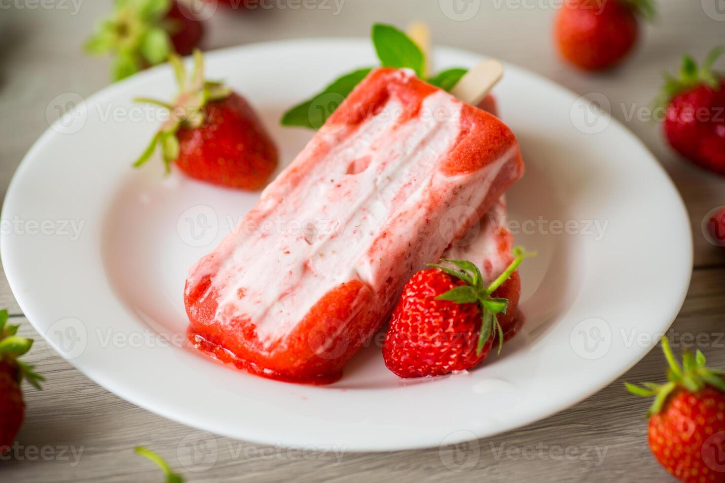homemade strawberry ice cream on a stick in a plate with strawberries photo