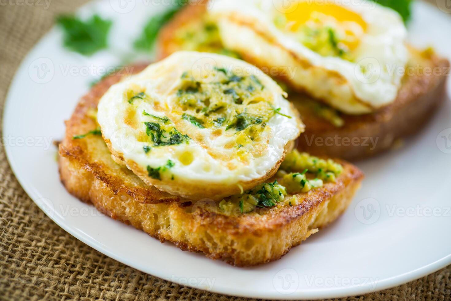 Fried croutons in batter with garlic and herbs and a fried egg in a plate. photo