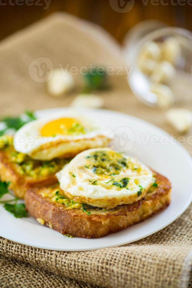 Fried croutons in batter with garlic and herbs and a fried egg in a plate. photo