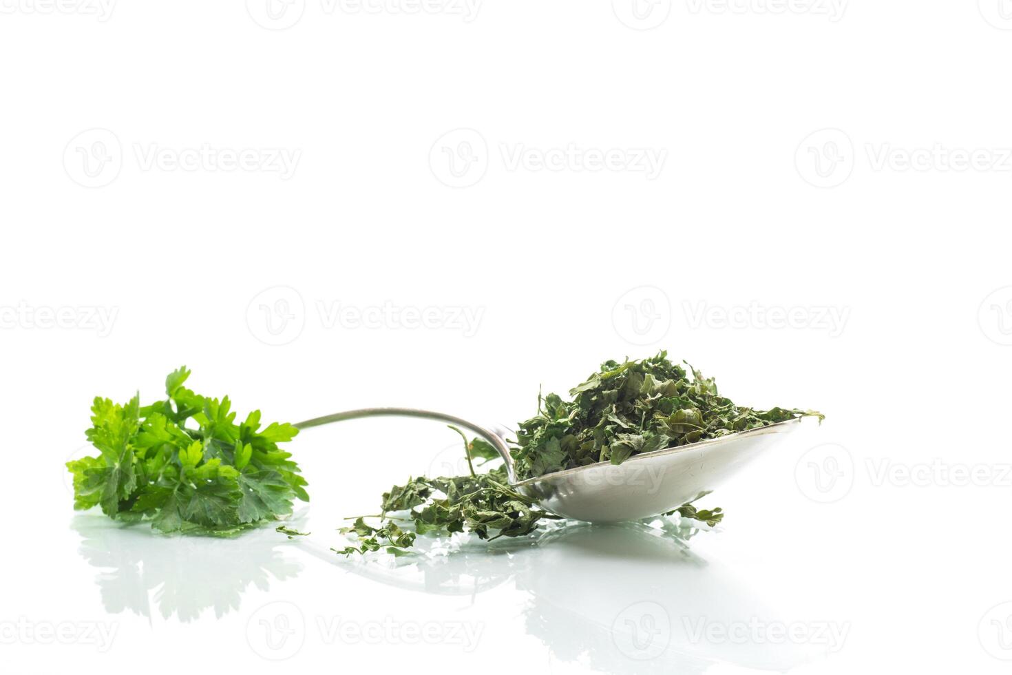 dried parsley in a spoon next to fresh herbs. photo