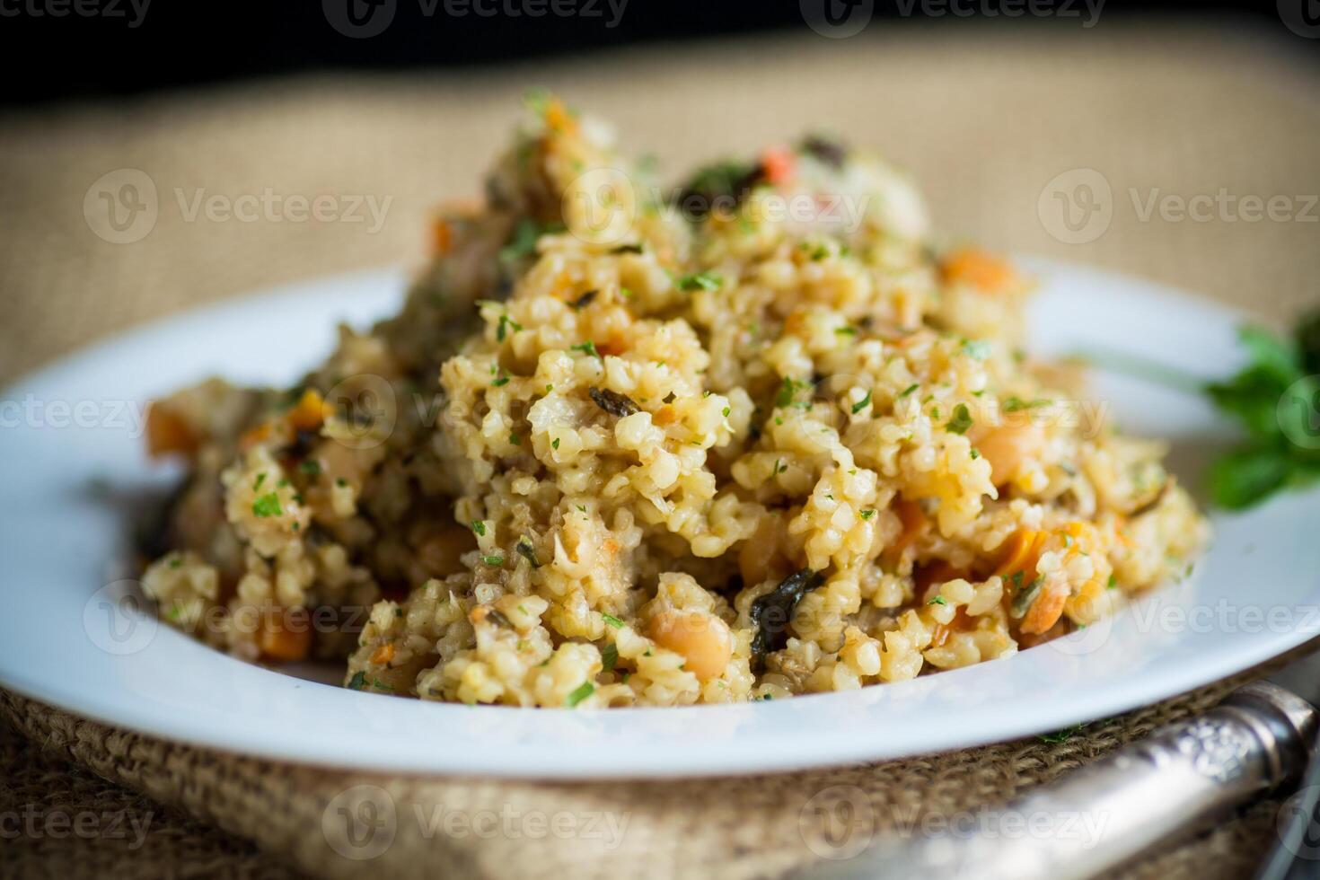 cooked bulgur with vegetables, carrots and dried mushrooms in a plate . photo