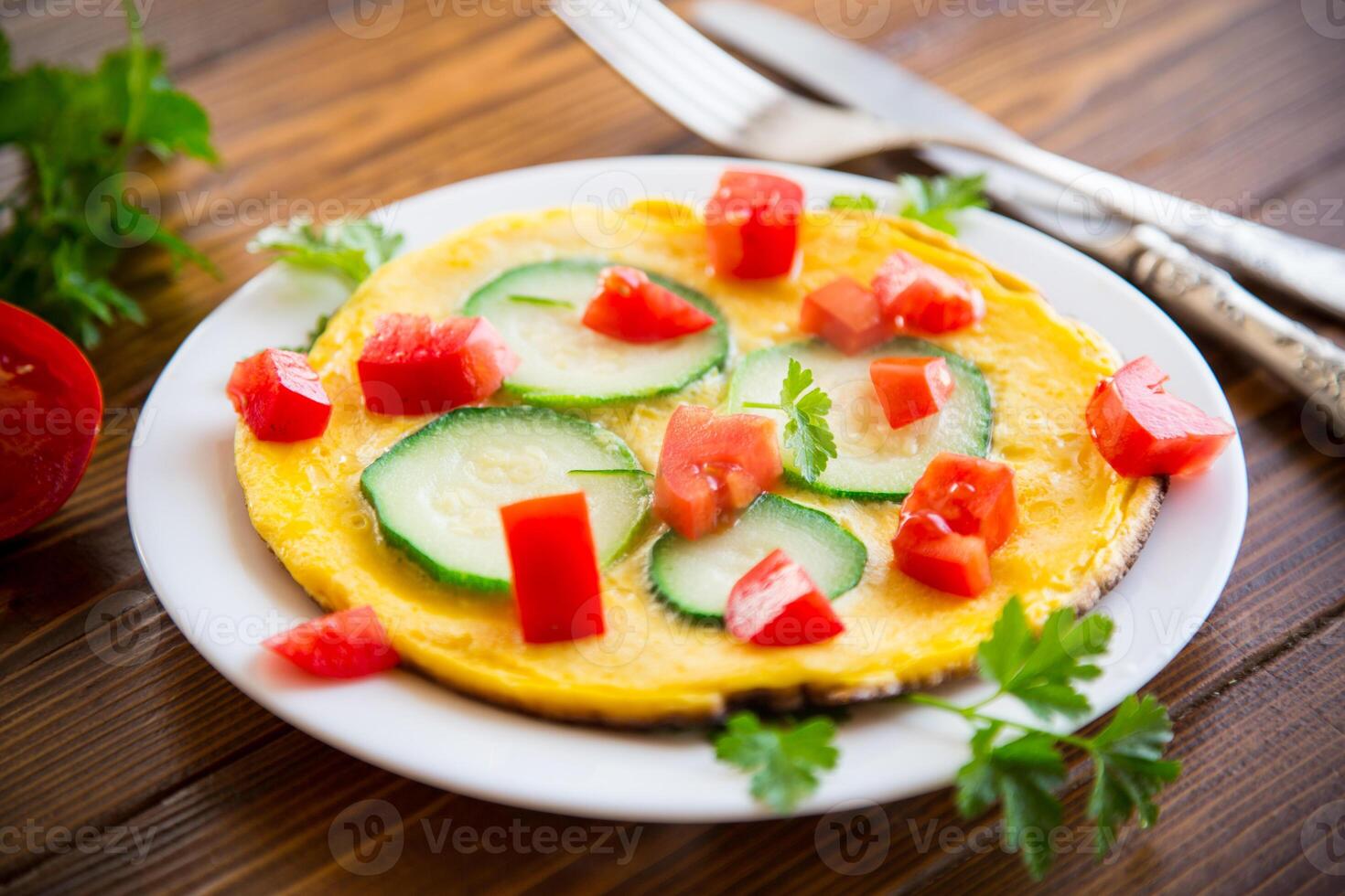 Fried omelet with zucchini, tomatoes, herbs in a plate photo