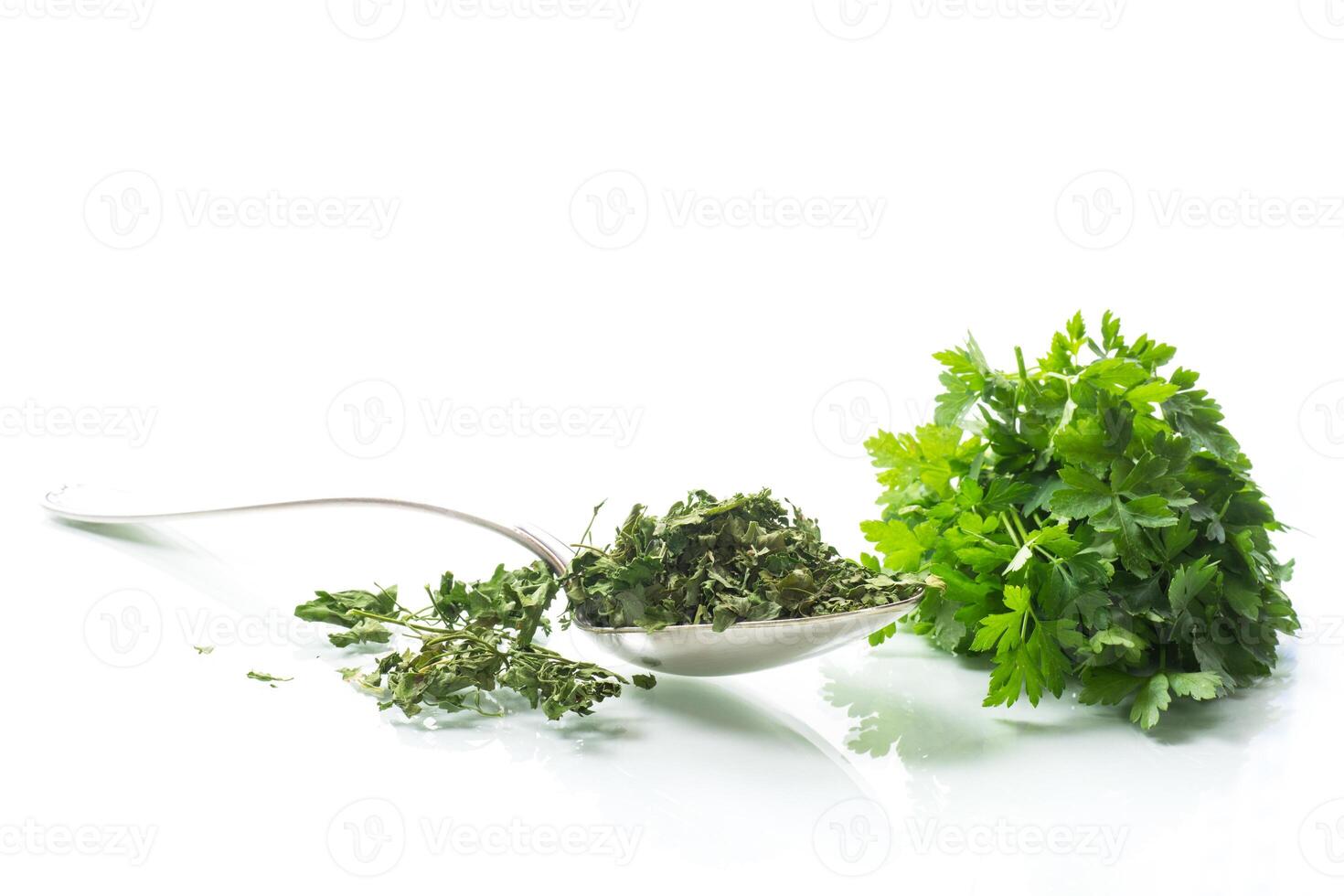 dried parsley in a spoon next to fresh herbs. photo