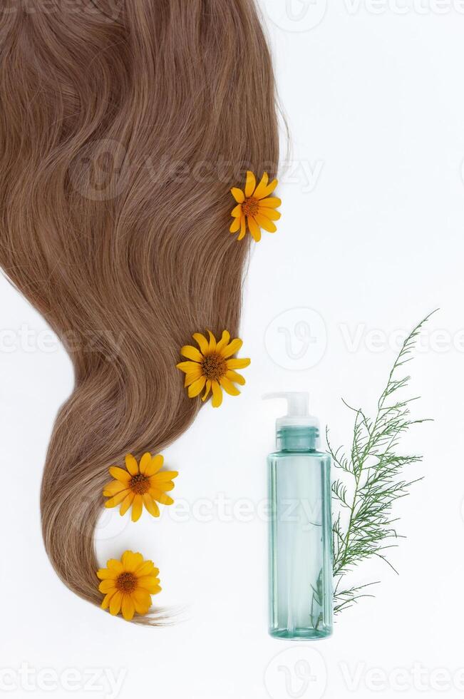 Healthy and beautiful hair. Cosmetic oil and flowers for hair on a white background.  Hair care. Copy space for text photo