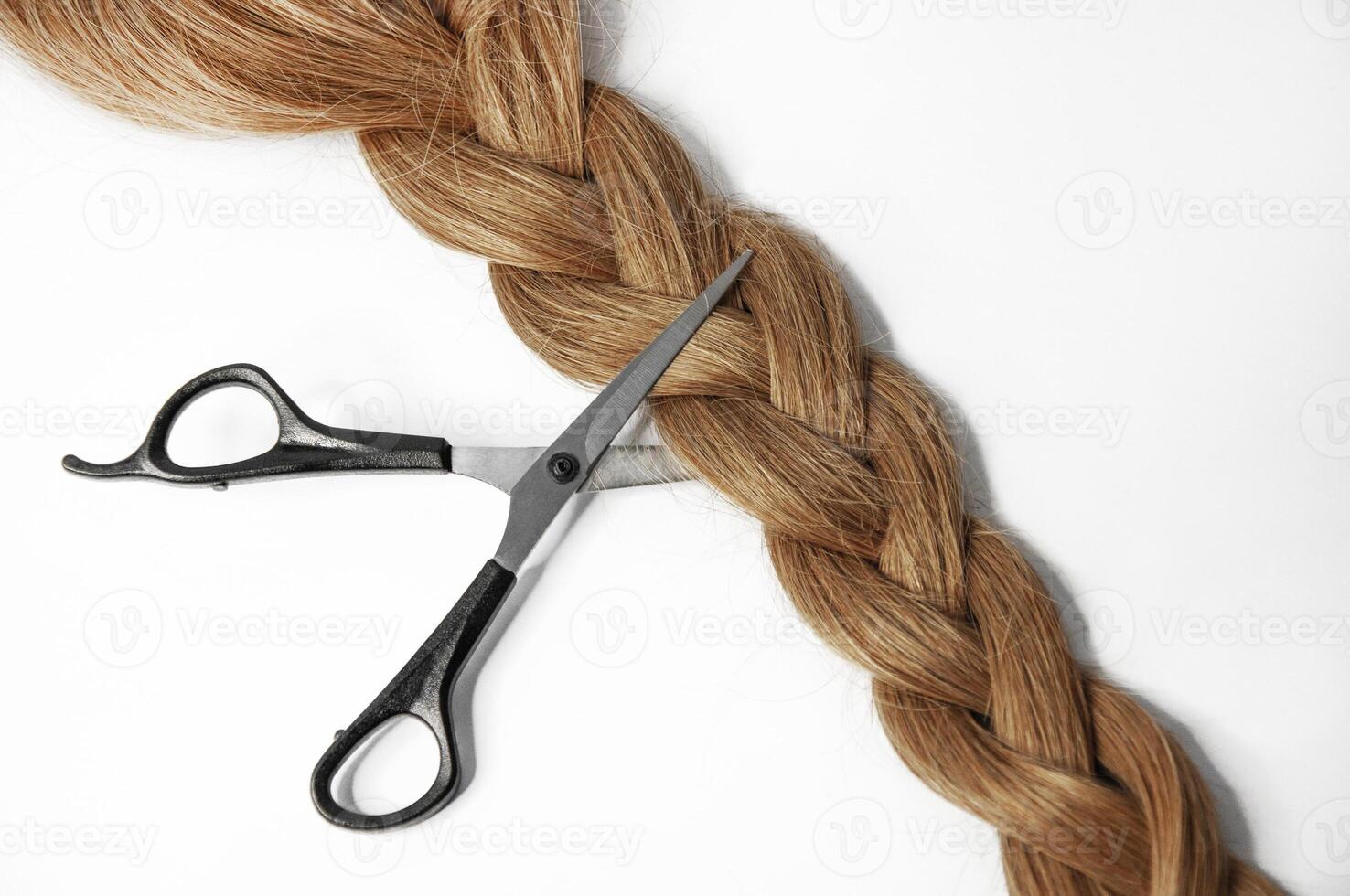 Scissors cut a long braid of hair on a white background photo