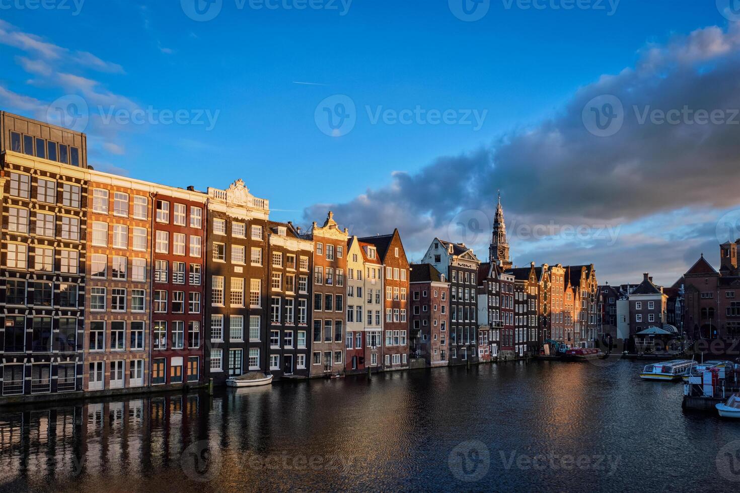 Hhouses and tourist boats on Amsterdam canal pier Damrak on suns photo