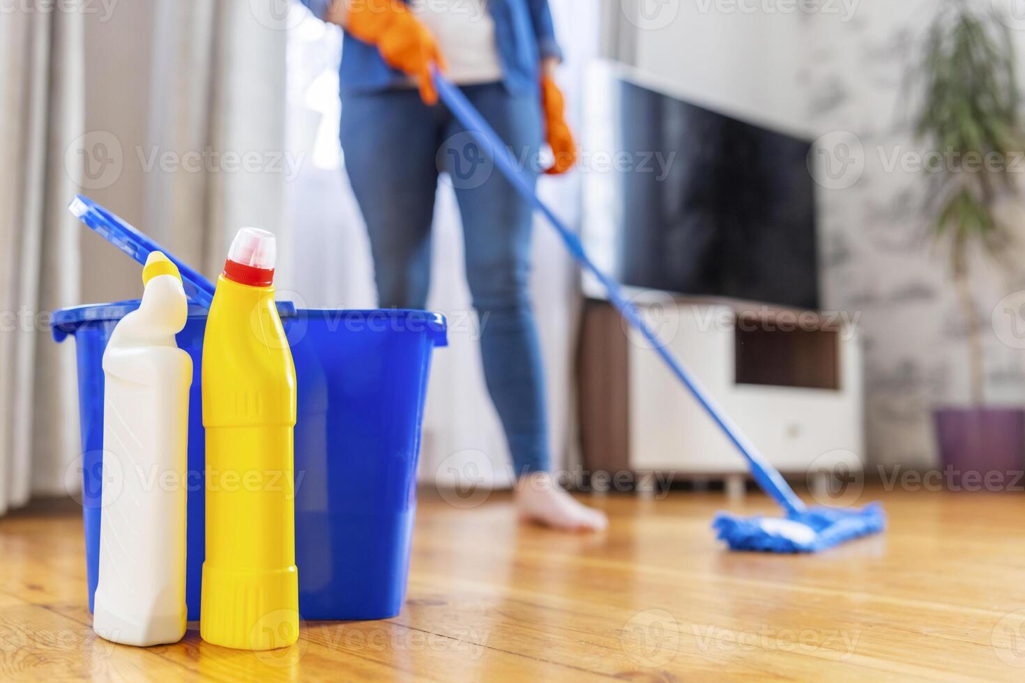 un joven mujer lavados el piso con un fregona en el vivo habitación foto