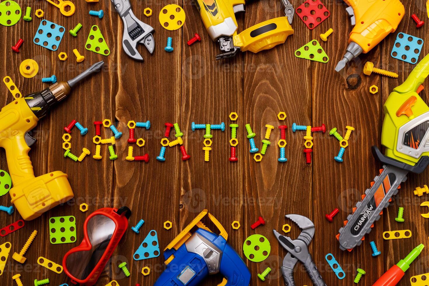 Toy tools, bolts and nuts with text CREATIVITY on wooden background photo