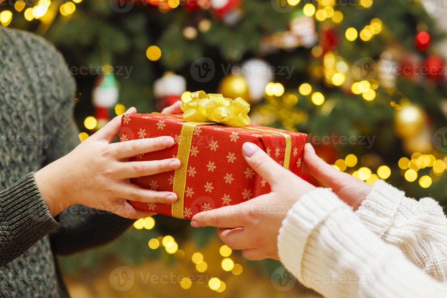 Hands of parent giving Christmas gift to child on Christmas tree background photo