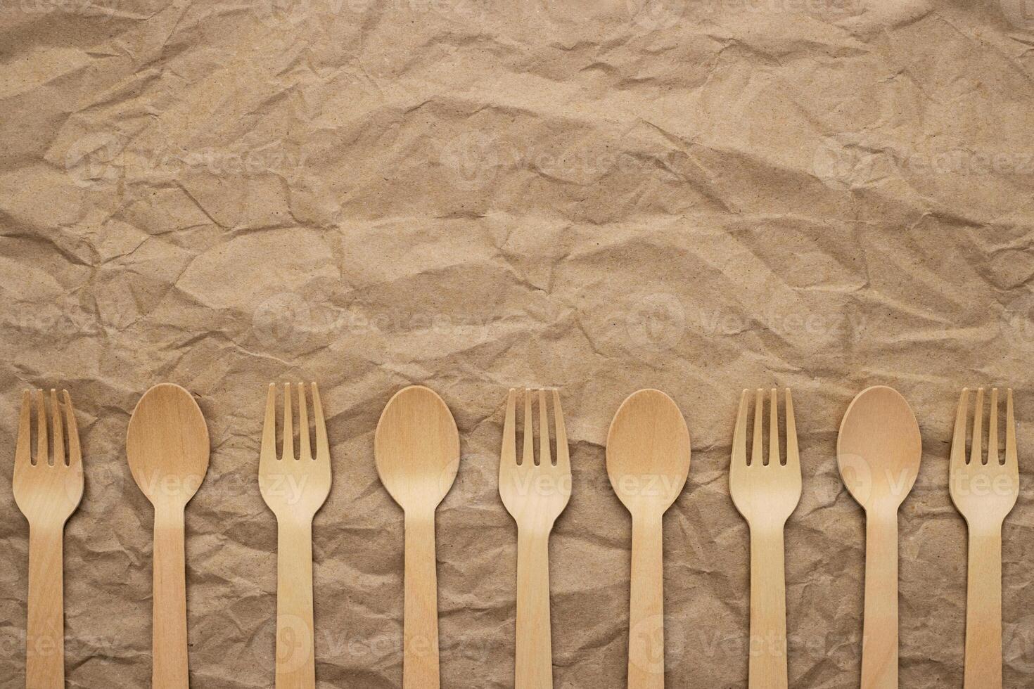 Set of wooden forks and spoons on crumpled paper background photo