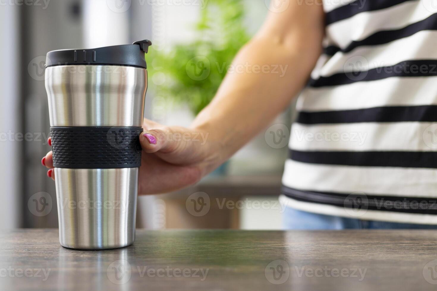 Holding a Travel Coffee Mug in a Striped Shirt photo