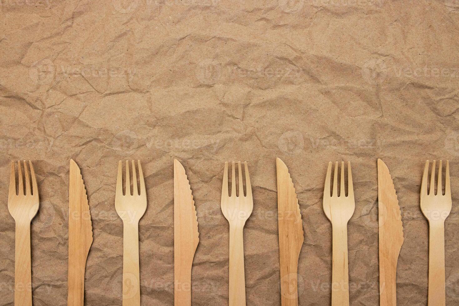 Set of wooden forks and knifes on crumpled paper background photo