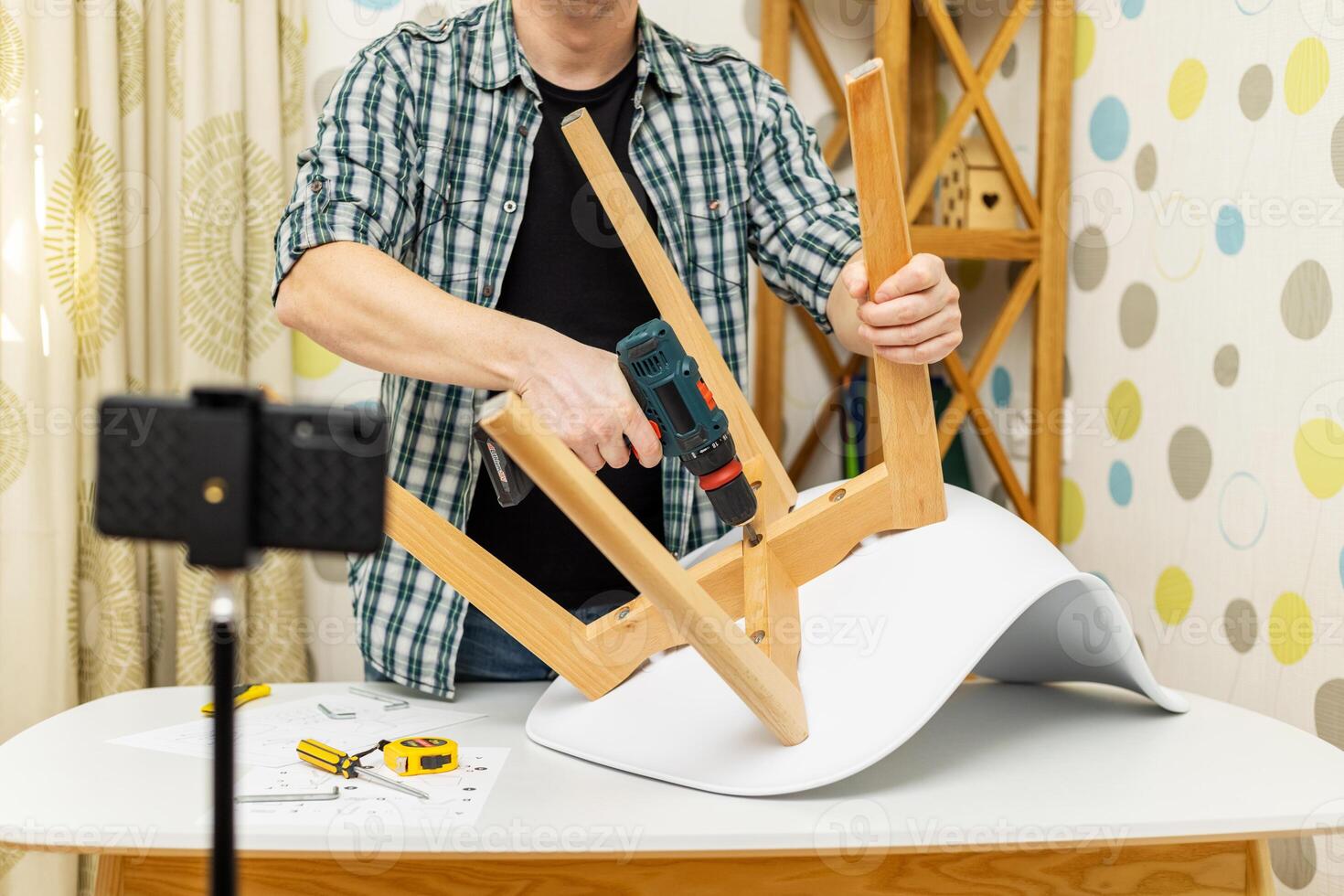 Handyman shows assembling chair, shooting video instructions on smartphone photo