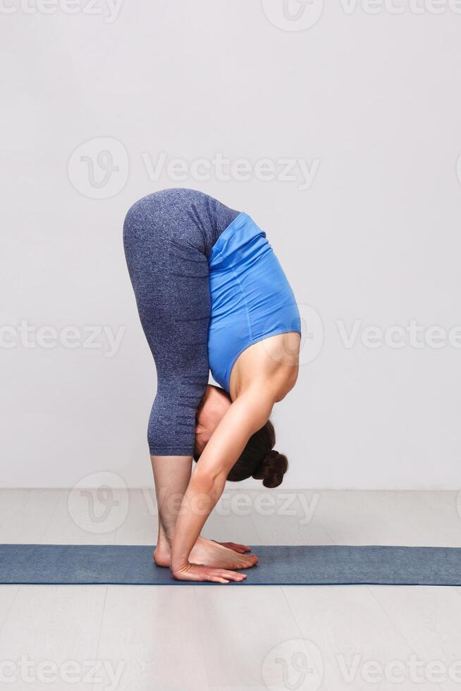 Woman doing yoga asana Uttanasana - standing forward bend photo