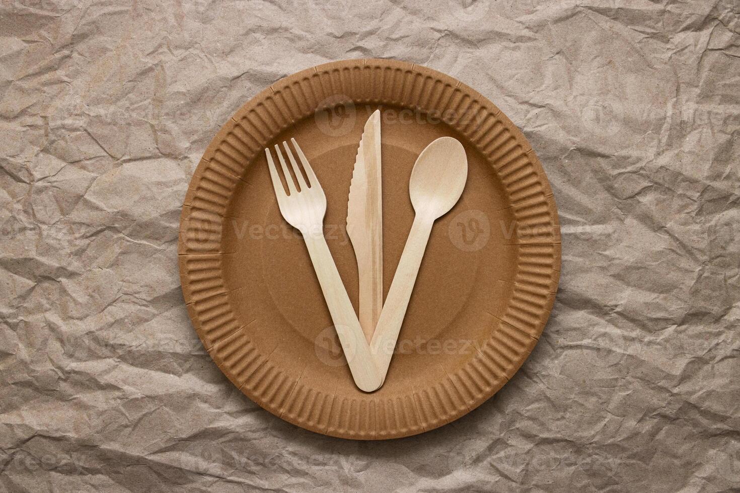 de madera tenedor, cuchara y cuchillo en cartulina plato en estropeado papel foto