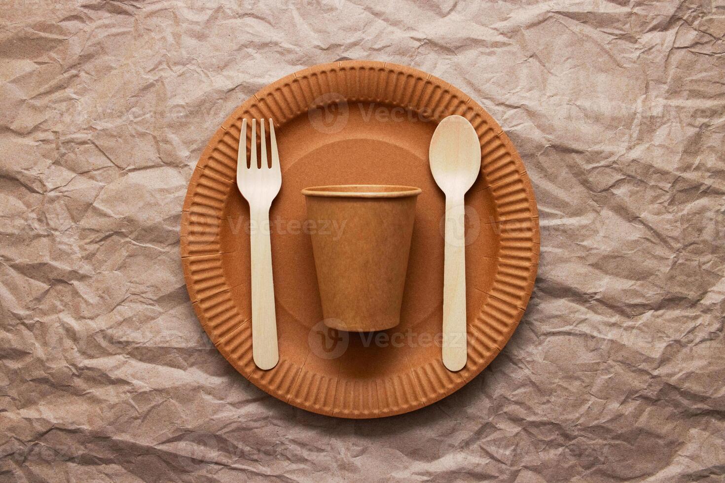 Wooden fork, spoon on cardboard plate on crumpled paper background photo