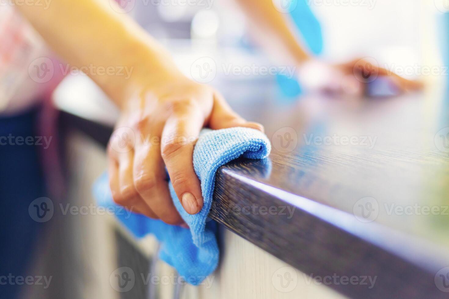 mujer mano limpieza el mostrador en el cocina con un azul microfibra paño foto