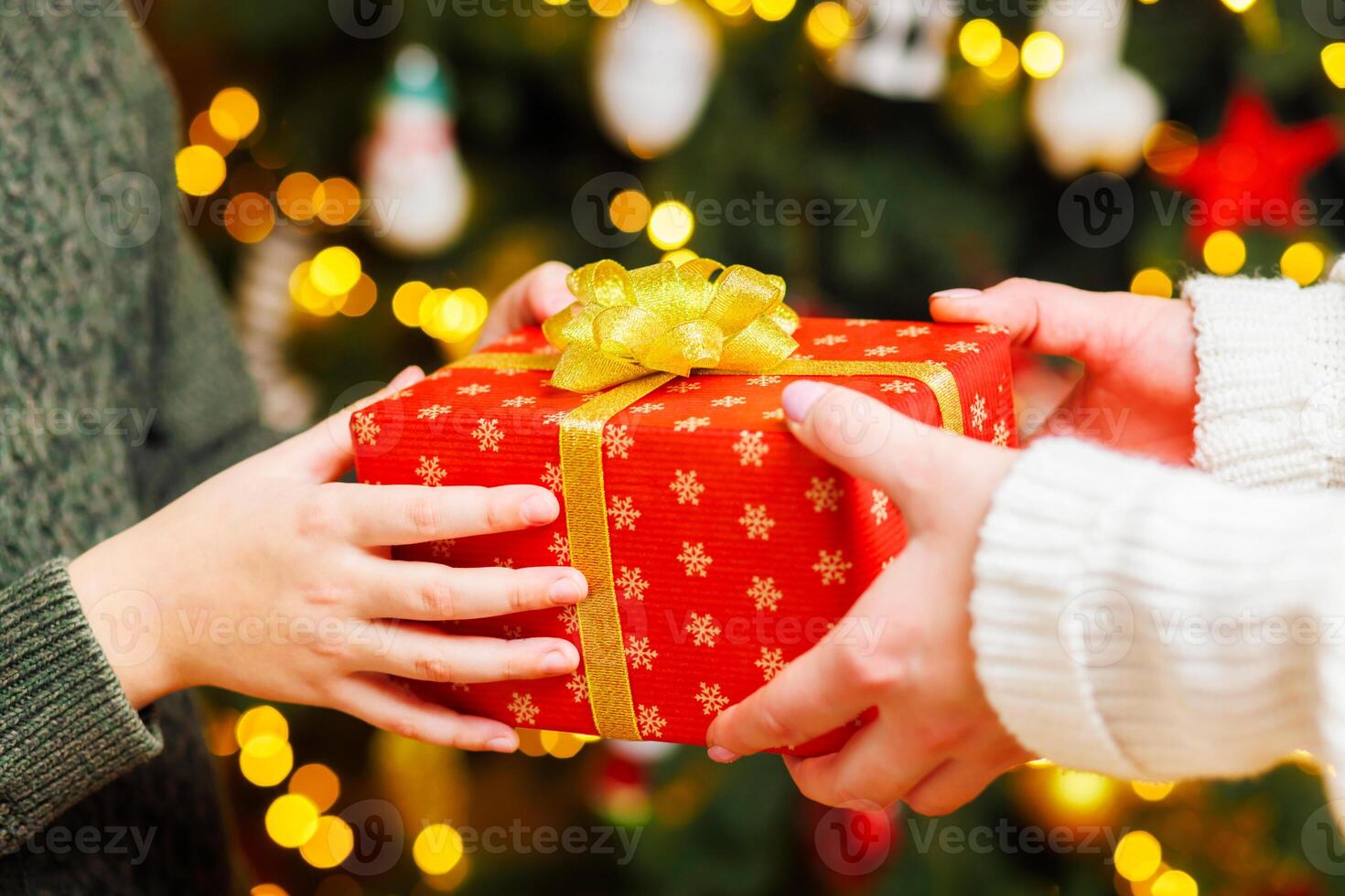 Hands of parent giving Christmas gift to child on Christmas tree background photo