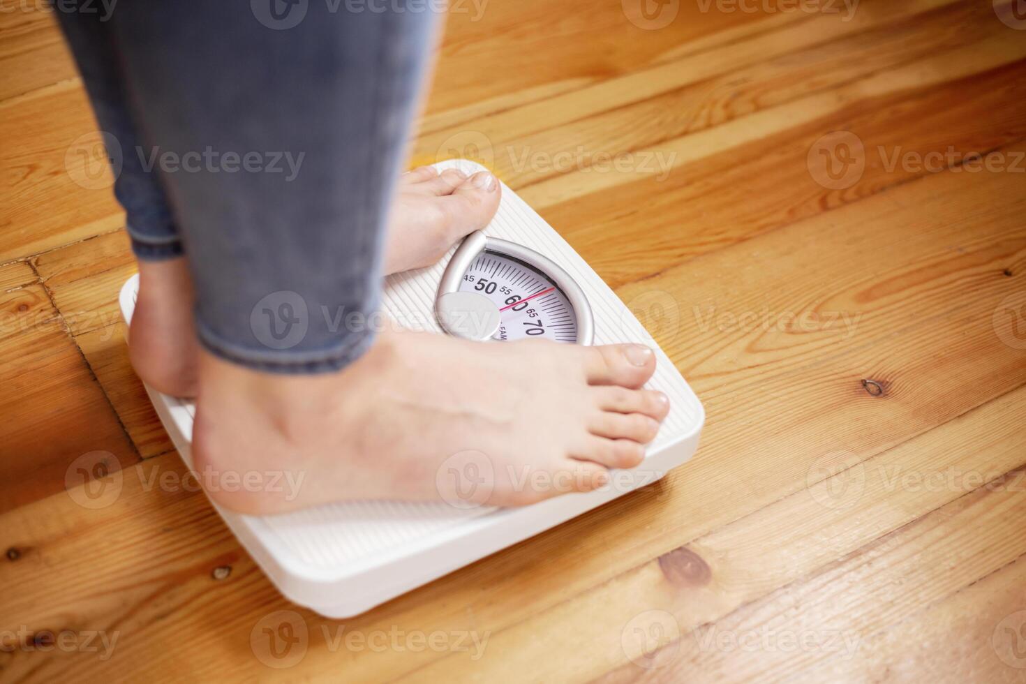 Womens bare feet stand on scales on the wooden floor photo